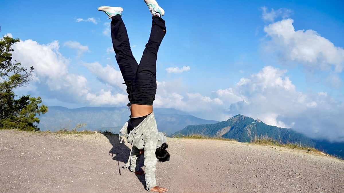 Person doing a handstand on a mountain path